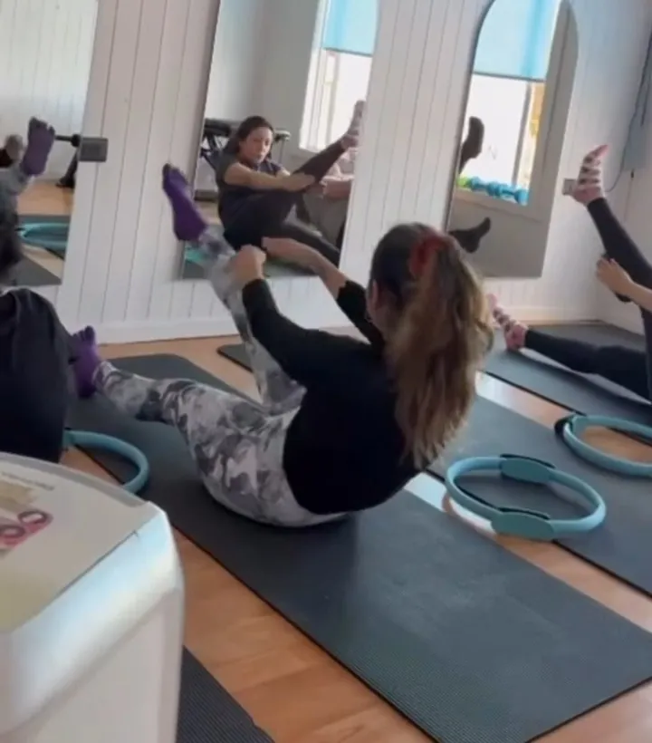 Sentada en equilibrio, brazos estirados hacia los pies